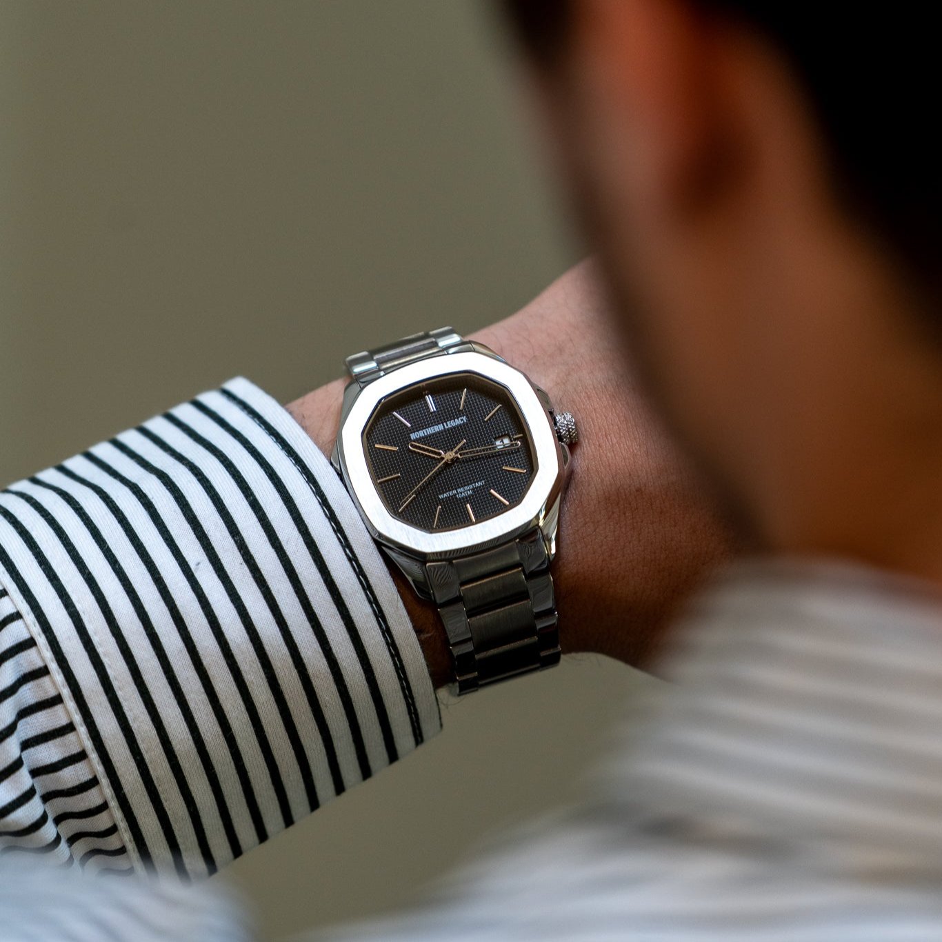 Fjord ur sort, sølvfarvet, sort urskive på en mands håndled, nærbillede